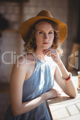 Portrait of beautiful young woman wearing hat standing at coffee shop