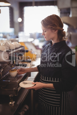 Young waitress making coffee from espresso maker