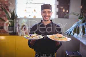 Portrait of smiling young waiter serving fresh food