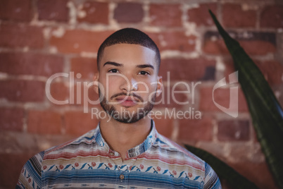 Close up portrait of confident young male customer standing against brick wall