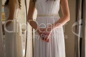 Midsection of bride in dress standing at home