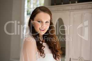 Portrait of beautiful bride in wedding dress standing at home