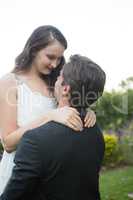 Romantic bridegroom lifting bride while standing in park