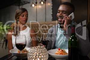 Woman looking at man while talking on mobile phone