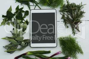 Various herbs with digital tablet on white background