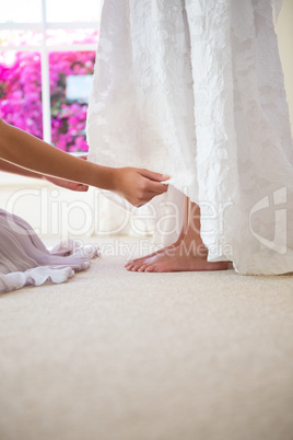 Bridesmaid adjusting bride dress in fitting room