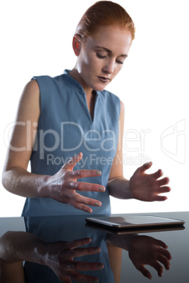 Businesswoman gesturing over digital tablet at table