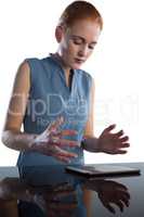 Businesswoman gesturing over digital tablet at table