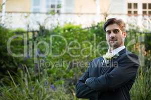 Portrait of handsome bride with arms crossed standing in park