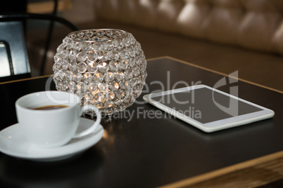 Close-up of coffee, digital tablet and lit candle on table