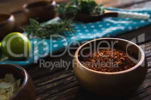 Red chili powder in a bowl on wooden table