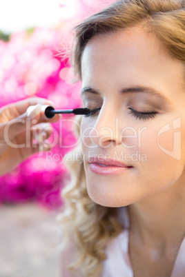 Cropped hand of woman applying mascara to bride