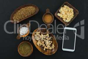Various spices in bowl with mobile phone on black background