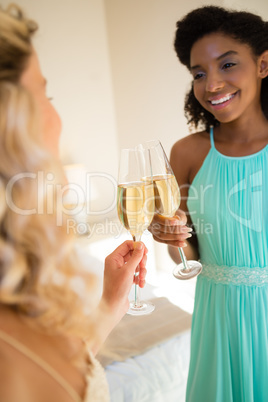 Bride and bridesmaid toasting drinks at home