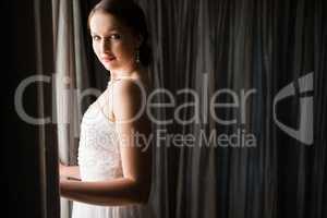 Portrait of beautiful bride standing by window at home
