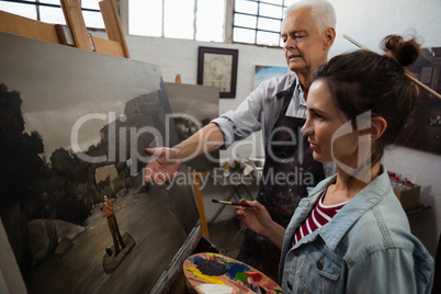 Senior man interacting while artist painting on canvas