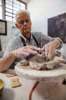 Attentive senior man molding clay