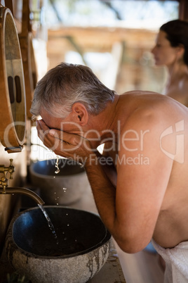 Man washing face from water in cottage