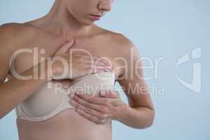 Mid section of young woman checking for breast cancer lumps