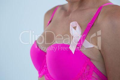 Mid section of woman in pink bra with Breast Cancer Awareness ribbon