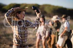 Shocked woman holding binoculars during safari vacation
