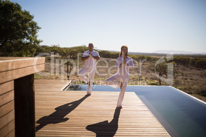 Couple practicing yoga on wooden plank