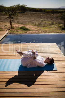 Woman practicing yoga on at poolside