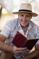 Portrait of happy man reading book in cottage
