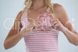 Pink ribbon seen through heart shape made by woman