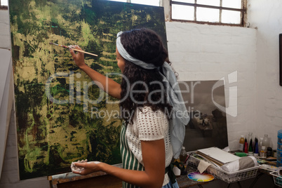 Attentive woman painting on canvas