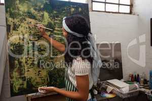 Attentive woman painting on canvas