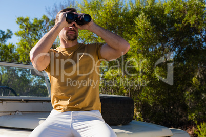 Man looking through binocular on off road vehicle