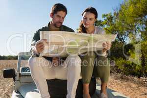 Couple reading map on off road vehicle with tire