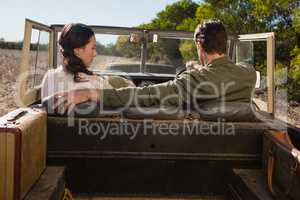 Rear view of man with woman driving off road vehicle