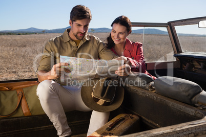 Smiling woman with man reading map in off road vehicle