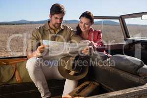 Smiling woman with man reading map in off road vehicle