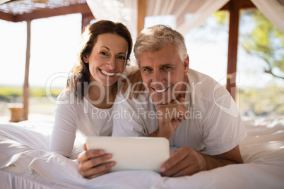 Portrait of happy couple using digital tablet on bed