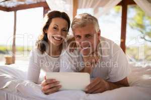 Portrait of happy couple using digital tablet on bed