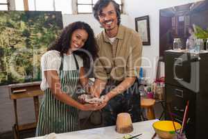 Portrait of man assisting woman in molding clay