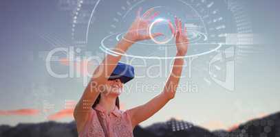 Composite image of young woman with arms raised looking through virtual reality simulator