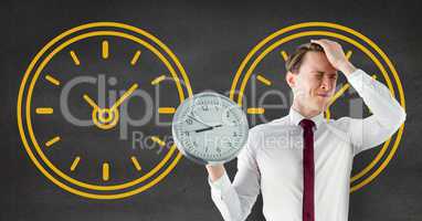 Worried business man holding a clock against background with clocks
