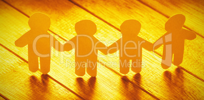 White paper cut out figures on wooden table