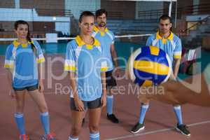 Cropped hand of coach holding ball practicing with volleyball players