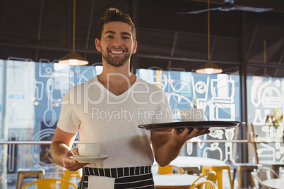 Portrait of smiling waiter holding tray