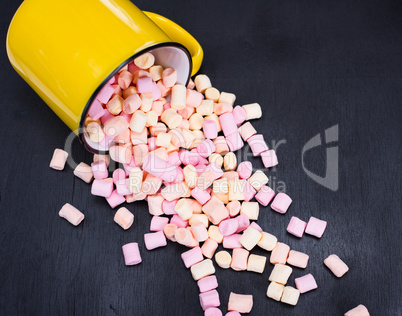 colorful marshmallows scattered from a yellow mug
