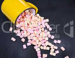 colorful marshmallows scattered from a yellow mug