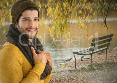 Man in Autumn with hat and scarf in park with pond