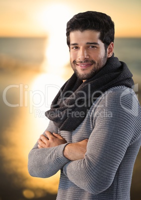 Man with folded arms by ocean sunset