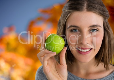 Woman in Autumn with apple in front of orange leaves