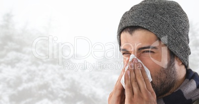 Man blowing his nose in bright snow forest
